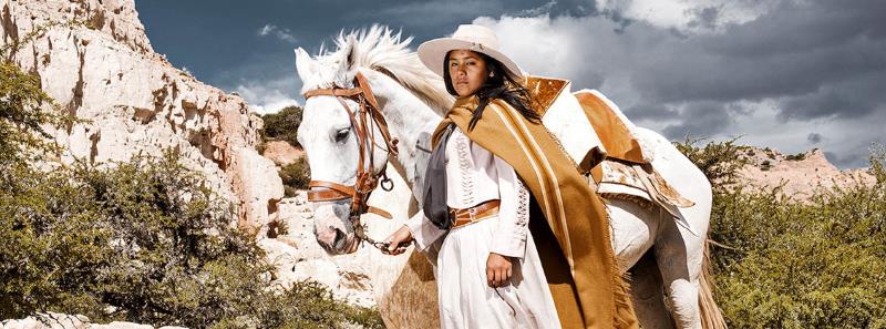 A northern Argentina cowgirl or Gaucha in traditional dress with her steed
